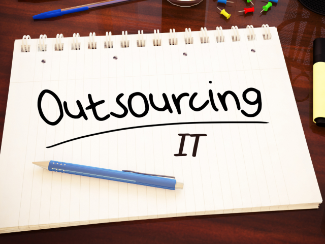 Notepad with writing on a page saying Outsourcing IT
