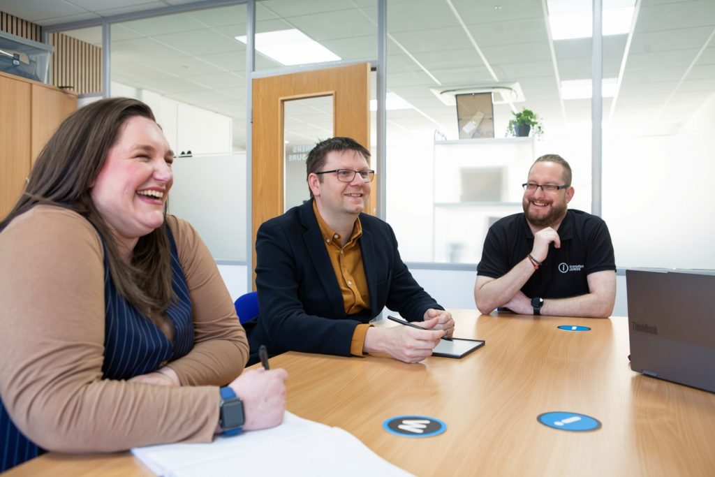 The Information Solutions team sharing a laugh around the meeting table